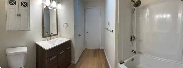 bathroom with toilet, tub / shower combination, wood finished floors, and vanity