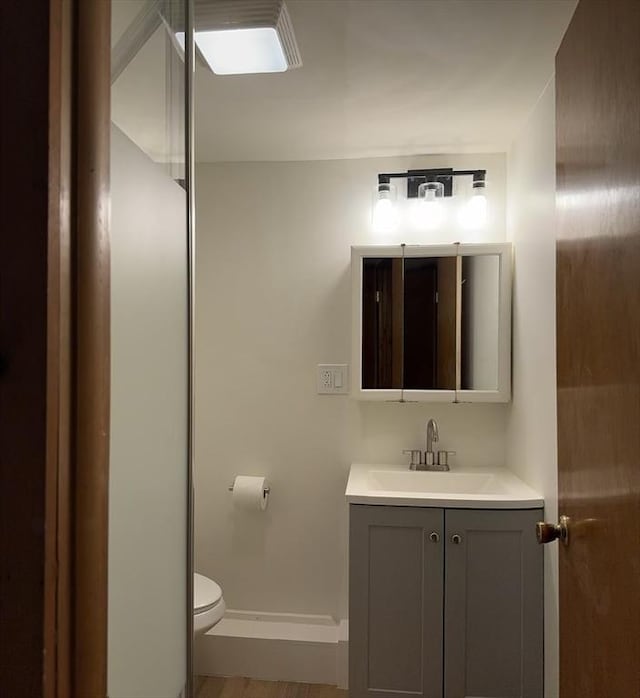 bathroom with baseboards, vanity, and toilet