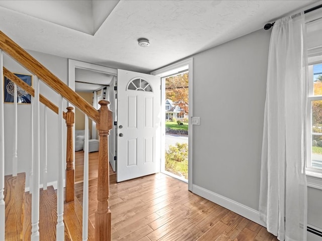 foyer with a baseboard heating unit, a textured ceiling, and light hardwood / wood-style floors