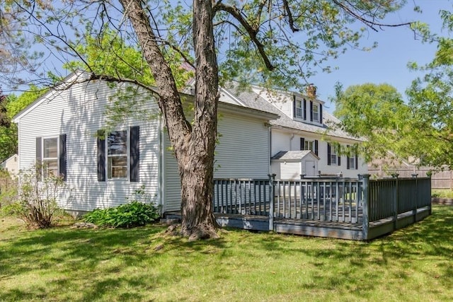 rear view of house featuring a deck, a yard, and a chimney