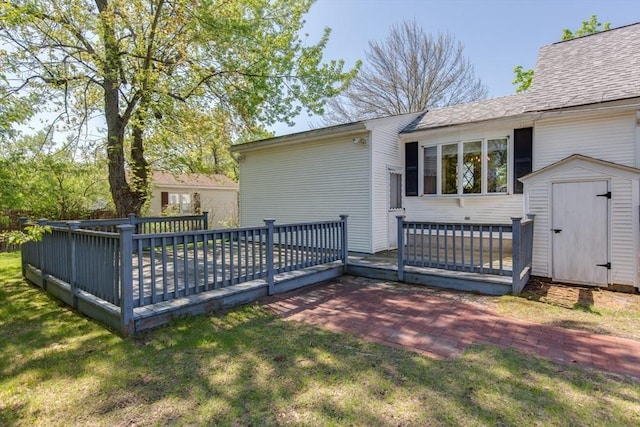 wooden deck featuring a storage unit, an outbuilding, and a lawn