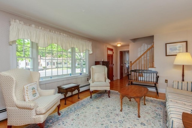 sitting room featuring stairway, wood finished floors, and a baseboard radiator