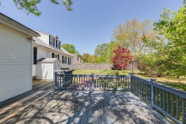 wooden deck with a storage shed, an outdoor structure, and fence