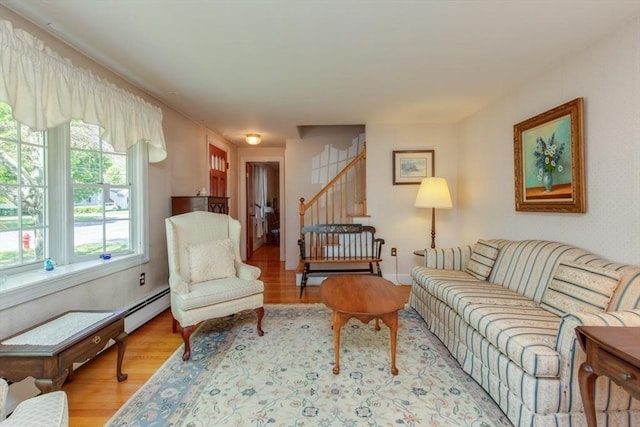 living room featuring wood finished floors, a baseboard heating unit, stairs, and baseboards