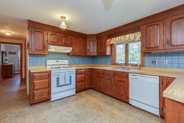kitchen featuring white appliances, under cabinet range hood, a sink, light countertops, and tasteful backsplash