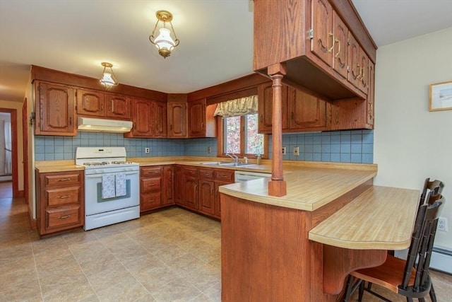 kitchen featuring white appliances, under cabinet range hood, a peninsula, light countertops, and decorative backsplash