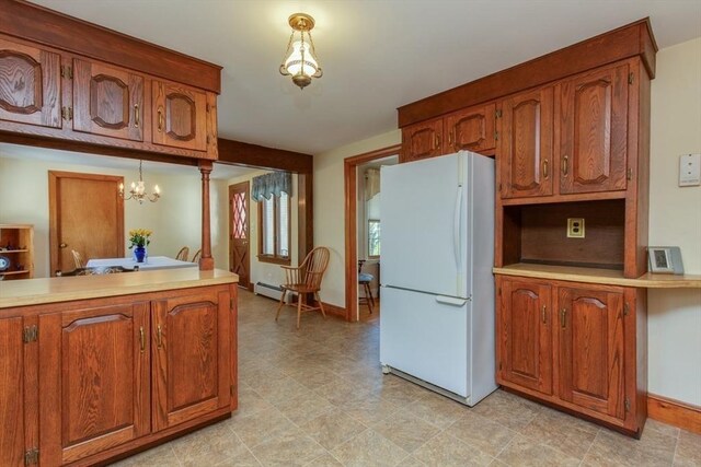 kitchen with freestanding refrigerator, brown cabinetry, and light countertops
