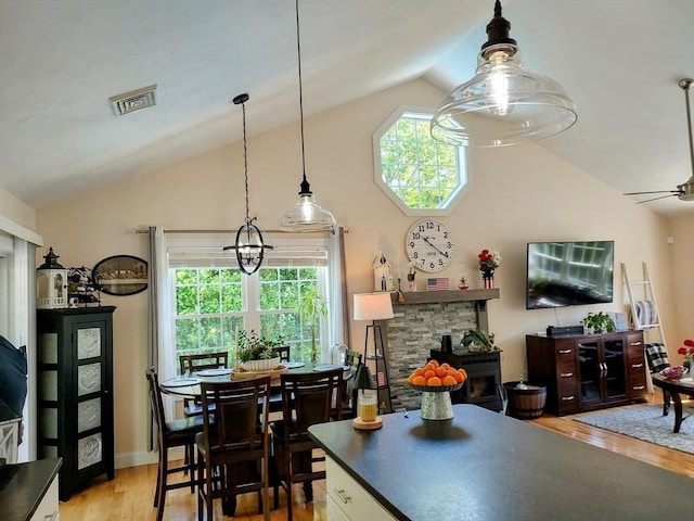 kitchen featuring vaulted ceiling, wood finished floors, plenty of natural light, a ceiling fan, and dark countertops