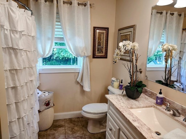 bathroom featuring plenty of natural light, toilet, vanity, and tile patterned floors