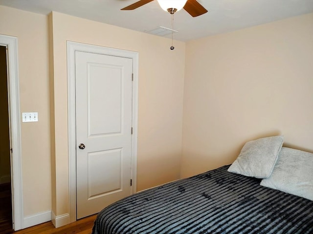 bedroom featuring wood finished floors, baseboards, and a ceiling fan