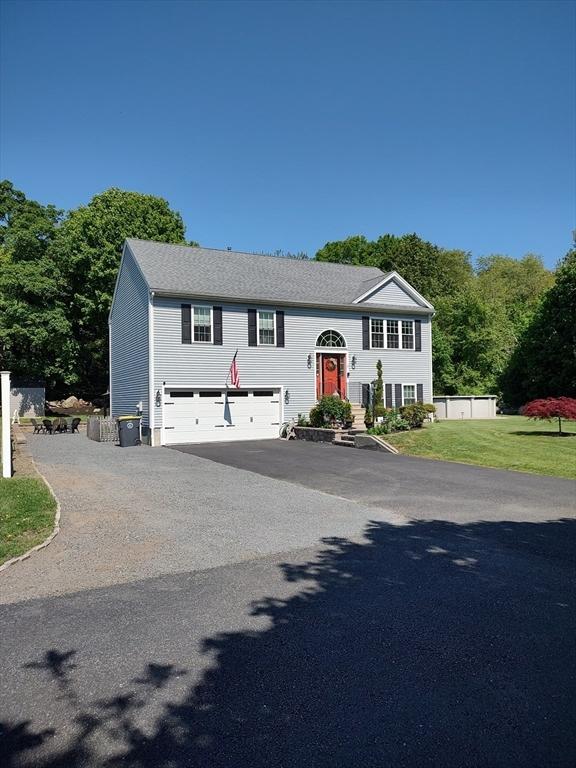 split foyer home with driveway, an attached garage, and a front lawn