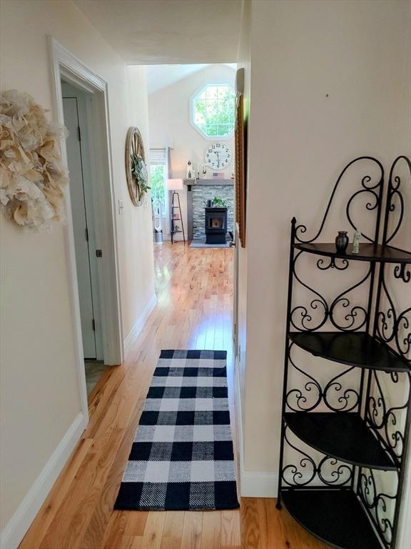 hallway with light wood-style flooring, baseboards, and lofted ceiling