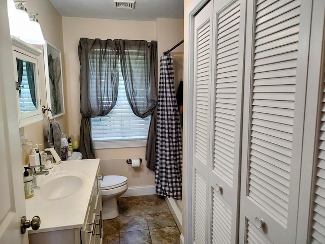 bathroom featuring a closet, toilet, vanity, a shower with curtain, and healthy amount of natural light