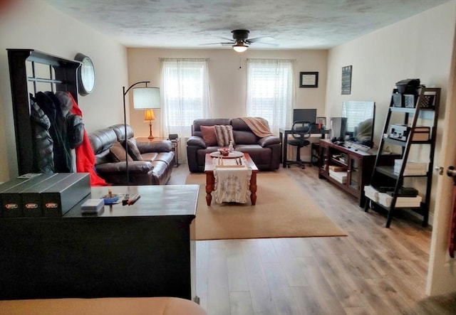 living room featuring wood finished floors, a ceiling fan, and a textured ceiling