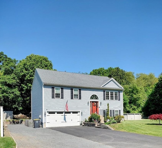 bi-level home with asphalt driveway, an attached garage, and a front yard