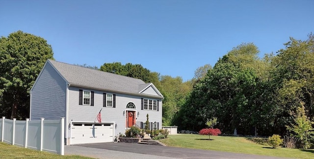 raised ranch with asphalt driveway, a garage, and a shingled roof