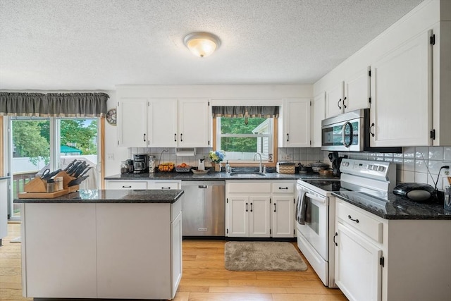 10 Manoogian Cir, Milford, MA 01757 - kitchen featuring appliances with stainless steel finishes, white cabinetry, light wood-style floors, a kitchen island, and a textured ceiling