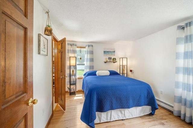 10 Manoogian Cir, Milford, MA 01757 - bedroom featuring a baseboard heating unit, light wood finished floors, and a textured ceiling