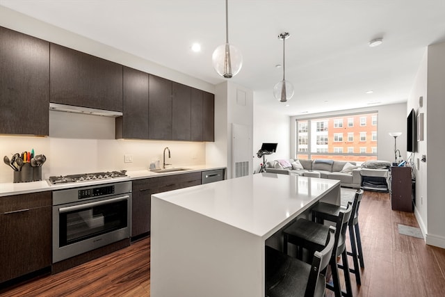 kitchen with a kitchen island, dark hardwood / wood-style flooring, appliances with stainless steel finishes, pendant lighting, and sink