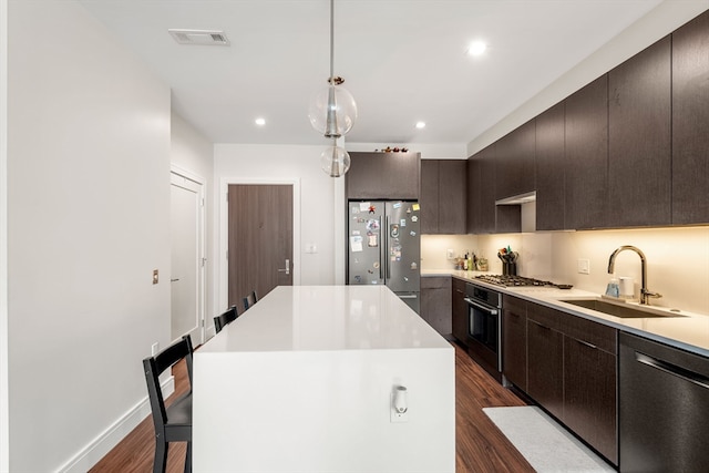 kitchen with a center island, sink, dark wood-type flooring, and appliances with stainless steel finishes