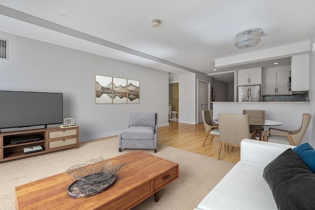 living area featuring recessed lighting, light wood-type flooring, visible vents, and baseboards