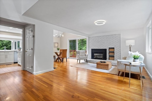 13 Long Ridge Rd, Acton, MA 01720 - living room featuring light wood-style floors, a brick fireplace, and a chandelier