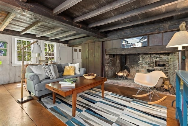 living area featuring beam ceiling, wood finished floors, wood walls, a fireplace, and wood ceiling