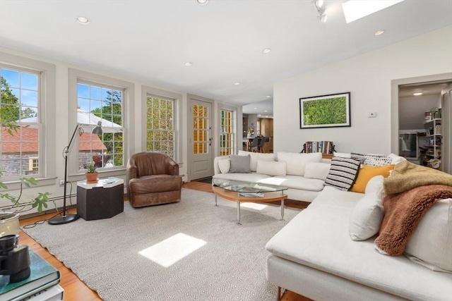 living area with wood finished floors, recessed lighting, a skylight, and lofted ceiling