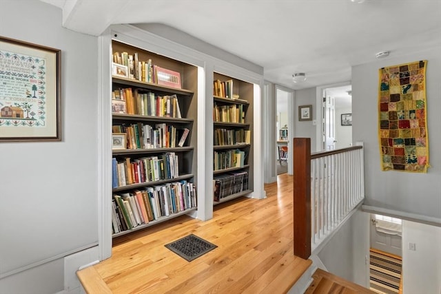 hall with an upstairs landing and wood finished floors