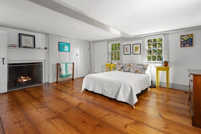 bedroom with a fireplace with flush hearth and hardwood / wood-style flooring