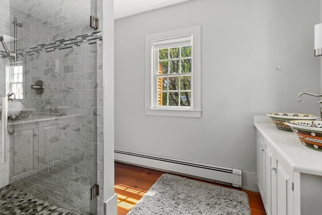 full bathroom featuring a baseboard heating unit, a stall shower, wood finished floors, and vanity