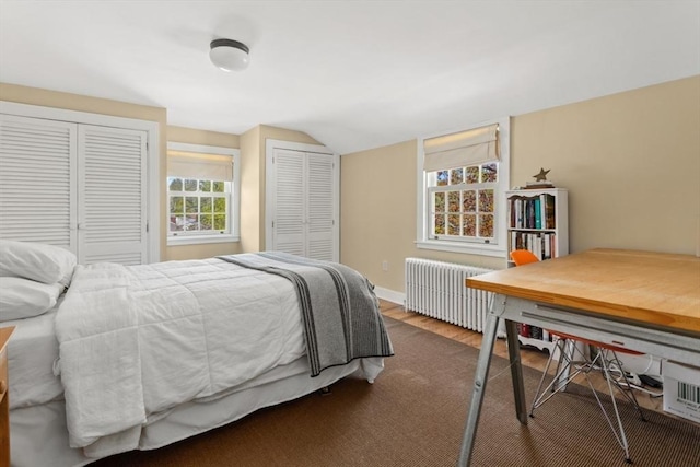 bedroom featuring multiple closets, radiator heating unit, lofted ceiling, and dark wood finished floors