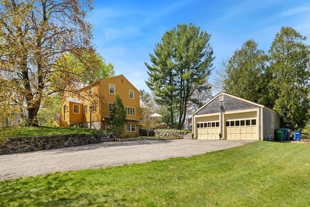 view of front facade featuring a detached garage, an outbuilding, and a front lawn