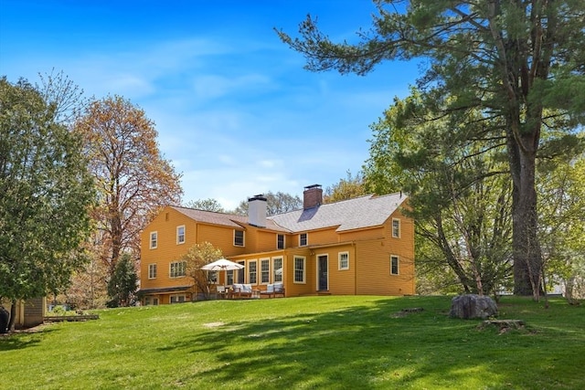back of property featuring a chimney and a lawn