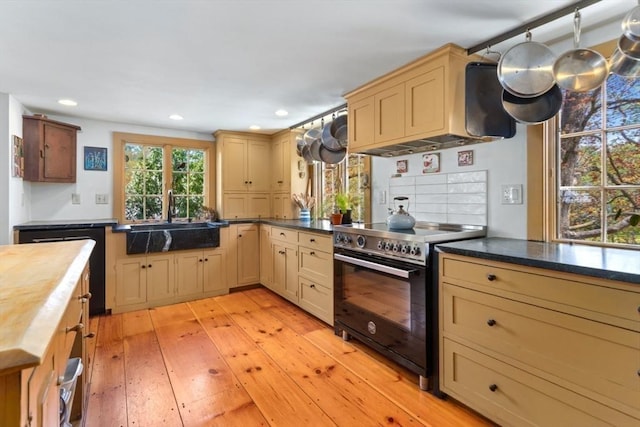 kitchen featuring black / electric stove, a sink, butcher block countertops, light wood finished floors, and recessed lighting