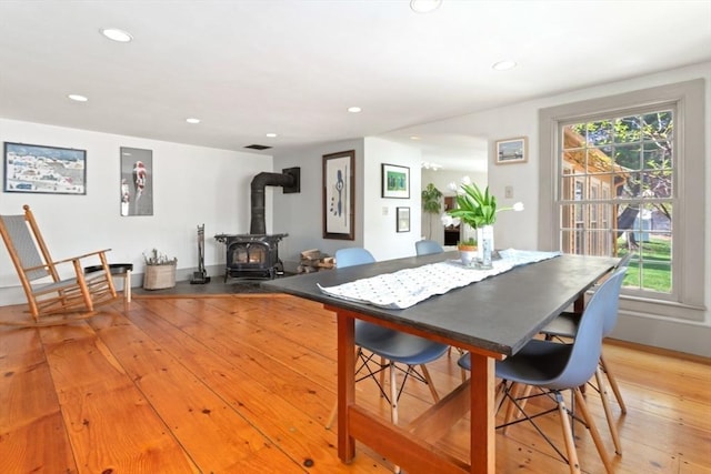 dining area featuring a wood stove, light wood finished floors, recessed lighting, and baseboards