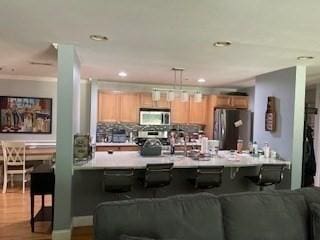 19 Broad St Unit 105, Merrimac, MA 01860 - kitchen with stainless steel appliances, light countertops, a peninsula, a breakfast bar area, and recessed lighting