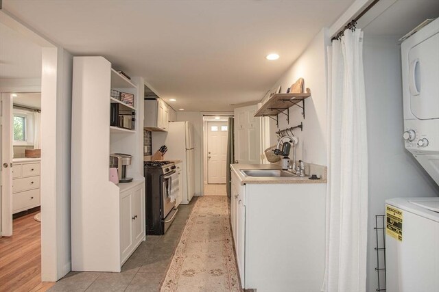 37 Raleigh Rd, Weymouth, MA 02189 - kitchen featuring stainless steel range with gas stovetop, a sink, stacked washer and clothes dryer, open shelves, and light countertops