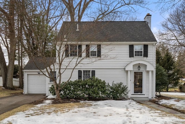 view of front of home with a shingled roof, a chimney, an attached garage, and aphalt driveway