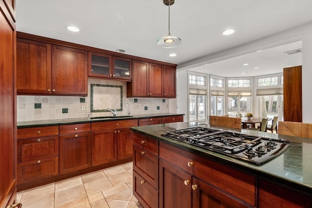 kitchen with black gas stovetop, a sink, visible vents, tasteful backsplash, and dark countertops