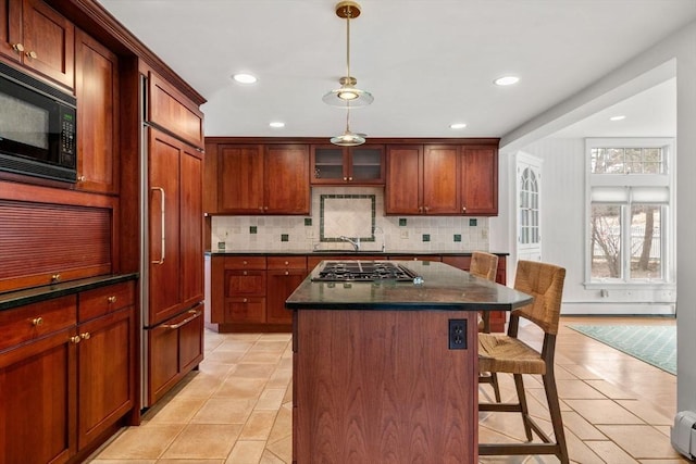 kitchen with a baseboard radiator, a kitchen breakfast bar, a center island, black microwave, and pendant lighting