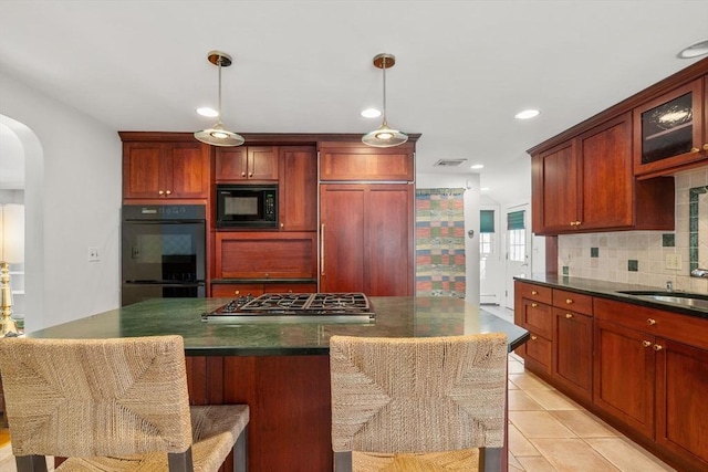 kitchen with arched walkways, light tile patterned floors, decorative backsplash, a sink, and black appliances