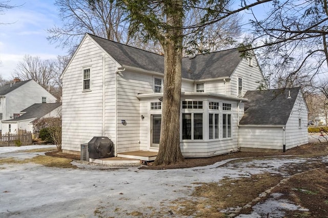 rear view of property featuring a sunroom, fence, and a wooden deck