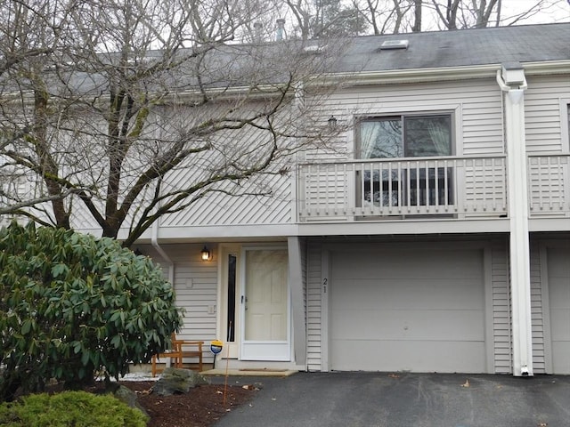 view of property featuring a garage, a balcony, and driveway