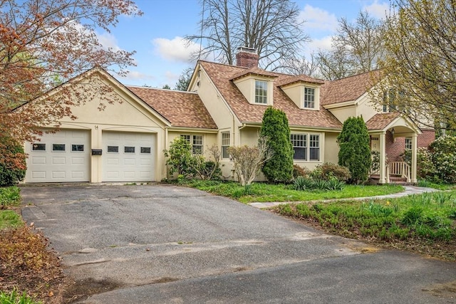 view of front of house featuring roof with shingles, aphalt driveway, a garage, stucco siding, and a chimney