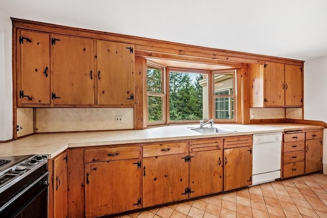 kitchen with white dishwasher, light countertops, brown cabinets, a sink, and range