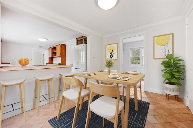dining space with baseboards, ornamental molding, and light tile patterned flooring