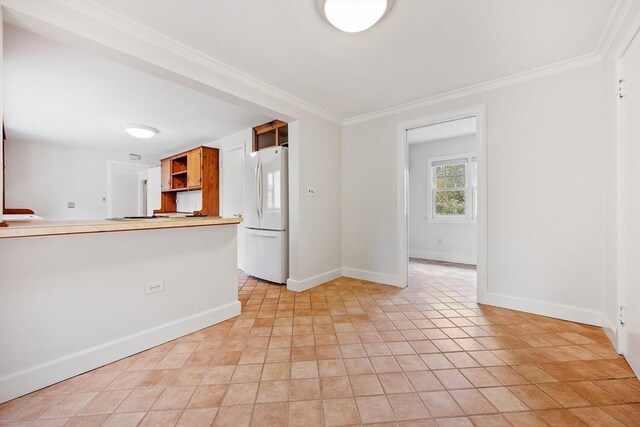 kitchen with open shelves, light countertops, baseboards, freestanding refrigerator, and ornamental molding