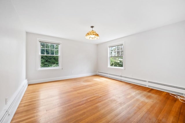 unfurnished room with plenty of natural light, light wood-style flooring, and baseboard heating