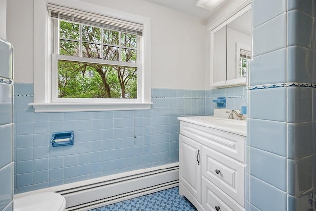 bathroom featuring vanity, toilet, a wainscoted wall, tile walls, and a baseboard radiator